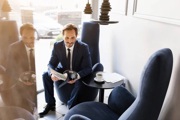 Empresário alegre entretendo com revista em cafetaria — Fotografia de Stock