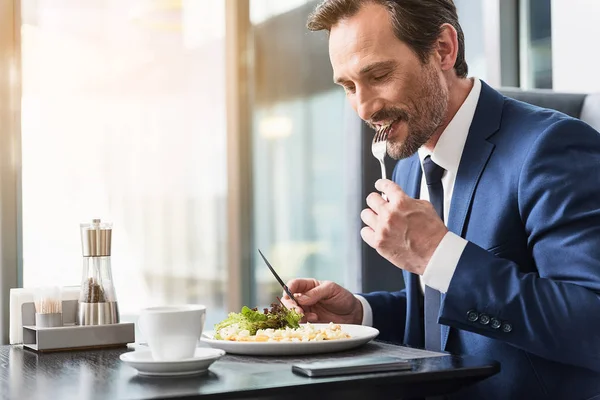 Cheerful businessman eating food in restaurant — Stock Photo, Image