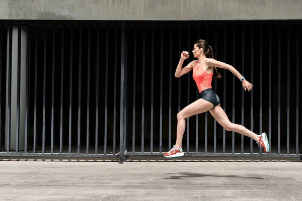 Vrolijke vrouwelijke jogger opleiding buitenshuis — Stockfoto