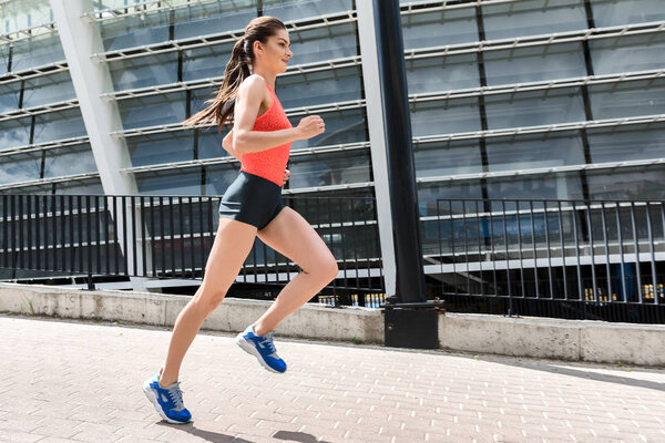 Joyful young woman running near stadium