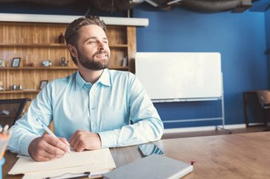 Neşeli genç adam yazma yaratıcı görev işveren Office sakallı