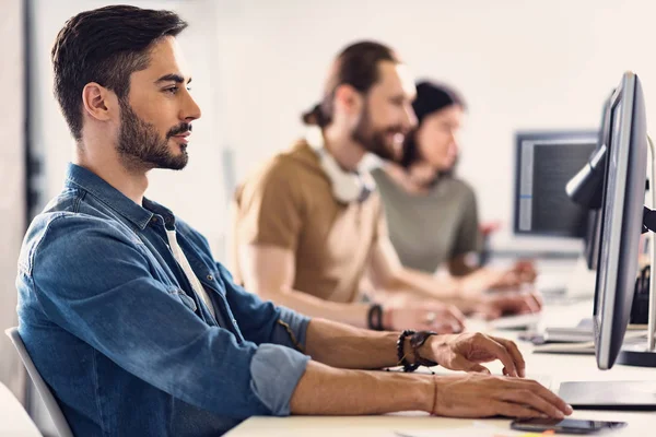 Lächelnder junger Mann tippt auf Tastatur am Schreibtisch — Stockfoto