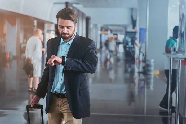 Adult man is checking time at departure area