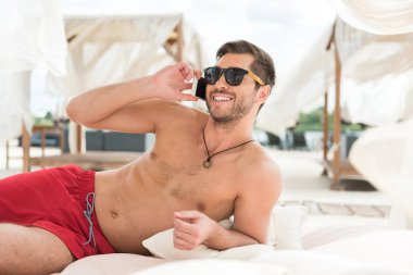 Neşeli genç sakallı erkek kumsalda Gadget'ı kullanma