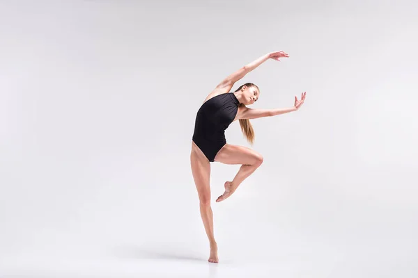 Serious young woman performing element of gymnastics choreography — Stock Photo, Image