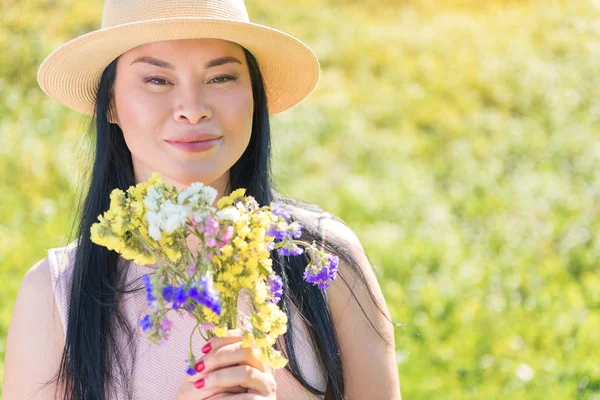 Feliz mujer asiática con flores relajándose en el campo —  Fotos de Stock