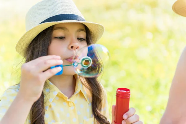 Lindo niño femenino soplando burbujas de jabón en la naturaleza —  Fotos de Stock