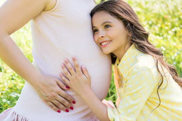 女性子供の屈託のない彼女の妊娠中の母親を抱きしめる — ストック写真