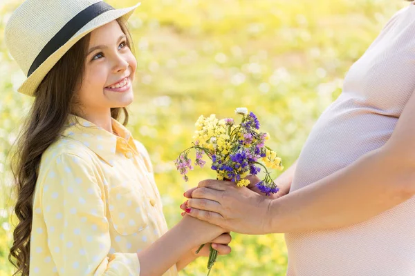 Lycklig dotter överlämna blommor till blivande mamma — Stockfoto