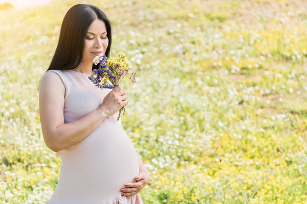 Feliz asiático embarazada mujer oliendo ramo en la naturaleza —  Fotos de Stock