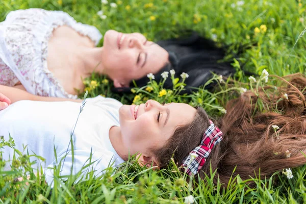 Putri ceria beristirahat di padang rumput dengan ibu — Stok Foto