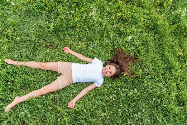 Nettes kleines Mädchen entspannt sich im Sommer auf dem Gras — Stockfoto