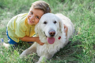 Neşeli çocuk hayvanını çayır üzerinde oynamaktan