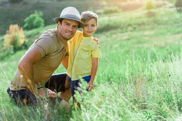 Веселий хлопчик обіймає тата на пасовищах — стокове фото
