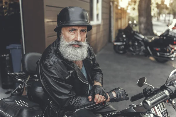 Alvorligt blik moden mand ved hjælp af motorcykel - Stock-foto
