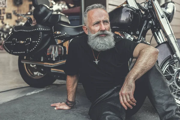Hombre viejo soñador localizando cerca de la motocicleta —  Fotos de Stock