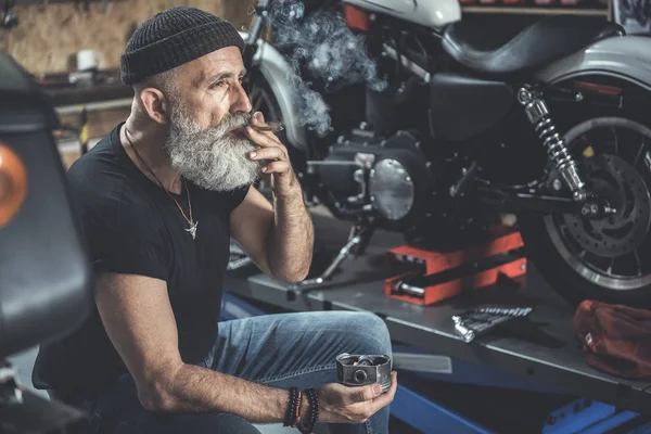 Thoughtful mature man smoking in garage