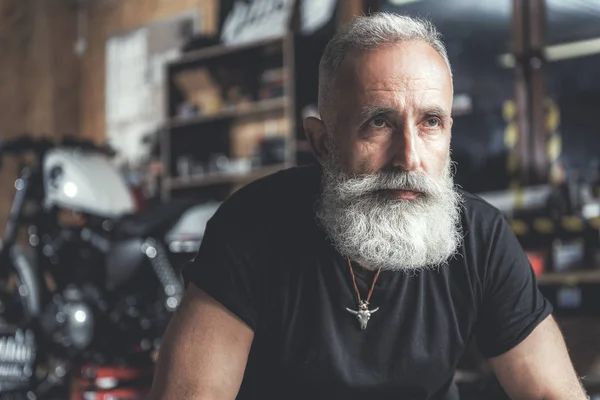 Confident aged man near bike looking up — Stock Photo, Image