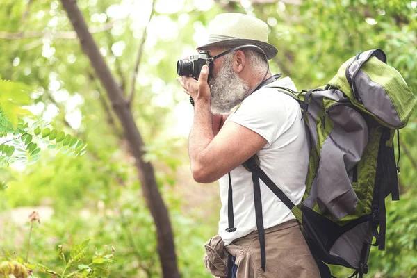 Concentrated old male tourist photographing forest — Stock Photo, Image