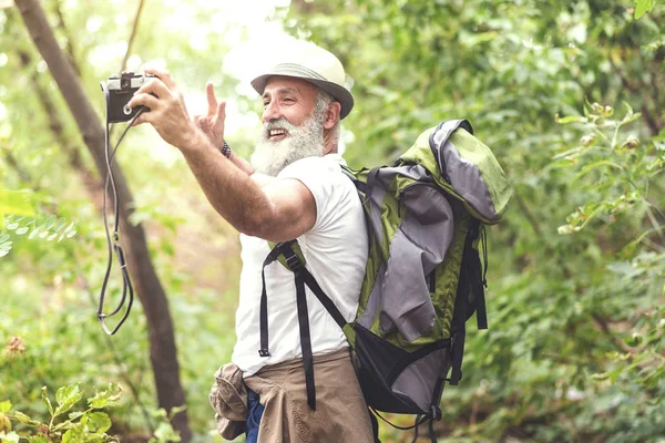 Happy senior tourist photographing himself in woodland — Stock Photo, Image