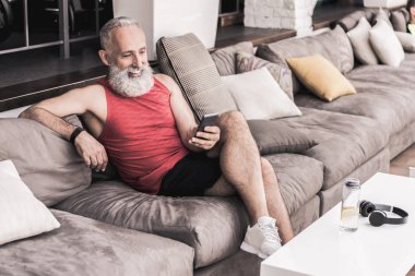 Spor salonunda dinlenirken cep telefonuyla olumlu kıdemli erkek