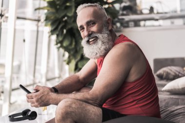 Neşeli kıdemli erkek spor salonunda iyi eğitimden sonra dinlenme zevk