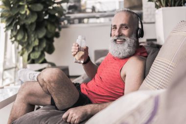 Neşeli yaşlı erkek spor merkezi kanepede oturuyor