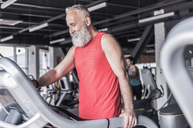 Neşeli yaşlı erkek fitness merkezinde zaman harcamaktadır