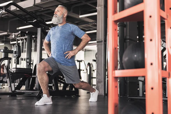 Elegante homem velho está desfrutando de treino no ginásio moderno — Fotografia de Stock