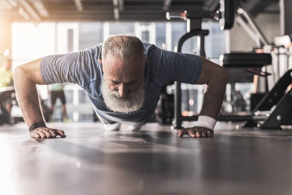 Barbudo velho pensionista masculino está tendo treino no ginásio — Fotografia de Stock