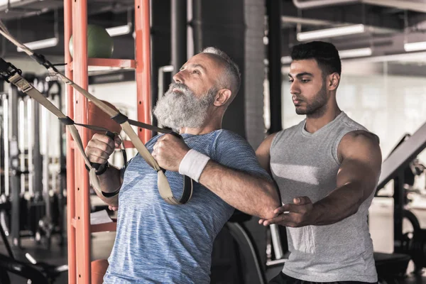 Olgun erkek egzersiz eğitmeni modern spor salonunda geçiriyor