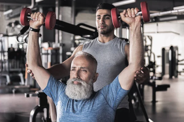 Ciddi eski sporcu antrenör ile modern bir spor salonu egzersizleri yapıyor — Stok fotoğraf