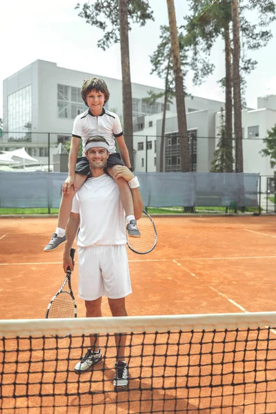 Ευτυχής χαμογελαστοί οικογένειας εντόπιση κοντά στο πλέγμα του τένις — Φωτογραφία Αρχείου