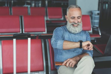 Glad smiling elder man waiting for plane clipart