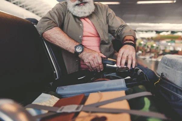 Серьезный старик смотрит на открытый чемодан — стоковое фото