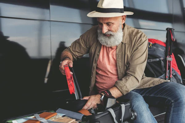 Anciano concentrado revisando su equipaje — Foto de Stock