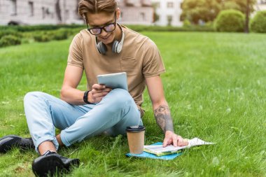 Neşeli erkek öğrenci açık havada Gadget'ı kullanma