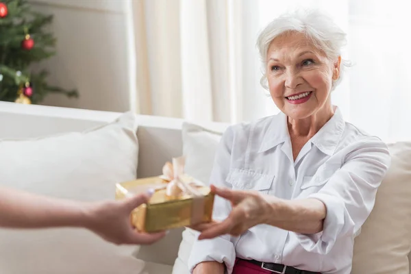 Радостная старшая леди берёт упакованную коробку — стоковое фото
