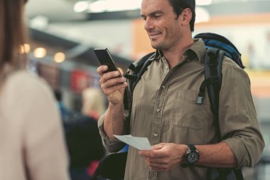 Neşeli adam modern Havaalanı'nda uçuşu için bekliyor