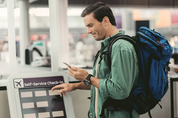 Chico alegre con el teléfono móvil está tocando la pantalla interactiva — Foto de Stock