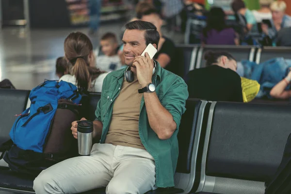 Neşeli adam kalkış alanında bankta oturuyor