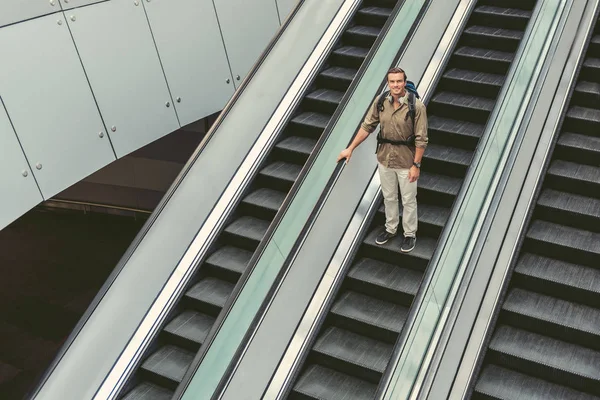 Счастливый взрослый парень стоит на движущейся лестнице — стоковое фото