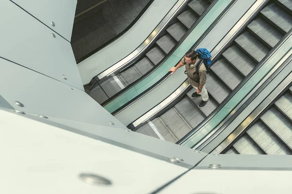 Joven viajero masculino está de pie en la escalera en movimiento —  Fotos de Stock