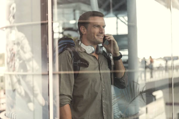 Позитивный парень стоит со смартфоном — стоковое фото