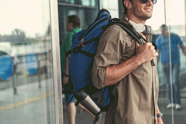 Positivo chico agradable con auriculares está saliendo del edificio del aeropuerto — Foto de Stock