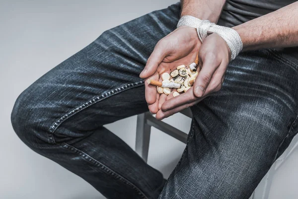 Mann hält schädliche Pillen und Zigarettenstummel in Handflächen — Stockfoto