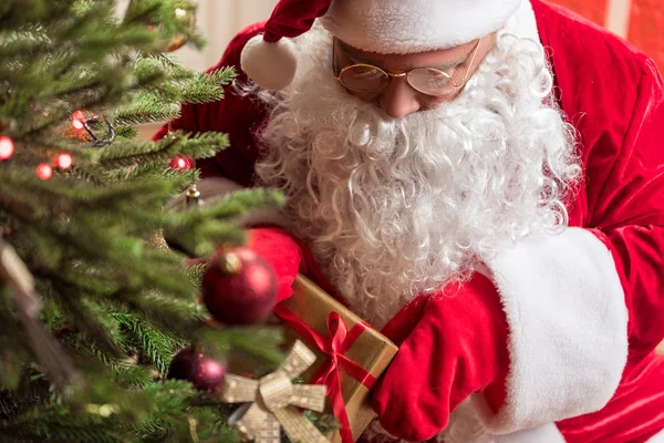 Secretive Santa Claus laying gift box to fir-tree — Stock Photo, Image