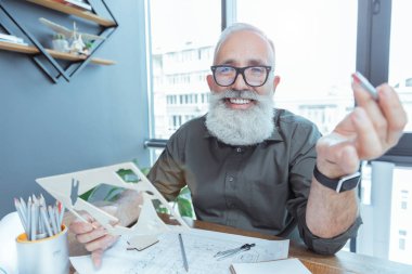 Holding kalıptır gülümseme ile pozitif gri saçlı mimar