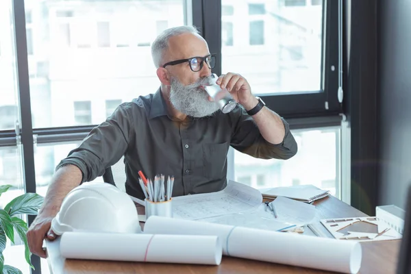 Serious architect in glasses is enjoying beverage — Stock Photo, Image
