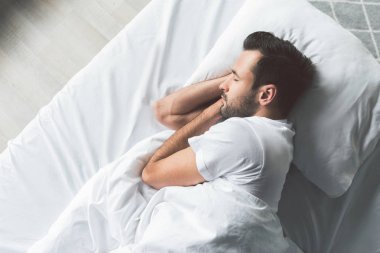 Yatakta uyuyan sevimli genç adam